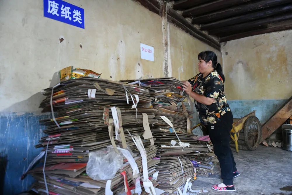 高晓静在牟定县蟠猫乡古岩村委会铜厂箐村废品收购点整理纸板（6月27日摄）。